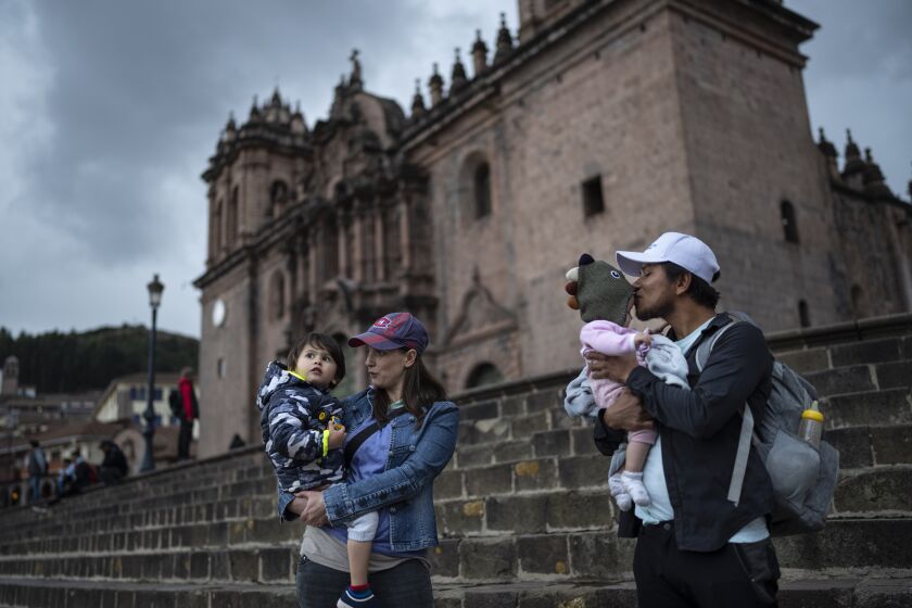 La británica Nathalie Zulauf, con hijo Kai, y su esposo Marco Gonzales, con su hija Willow, en los escalones de la Catedral, en Cusco, Perú, el miércoles 1 de febrero de 2023. (Foto AP/Rodrigo Abd)