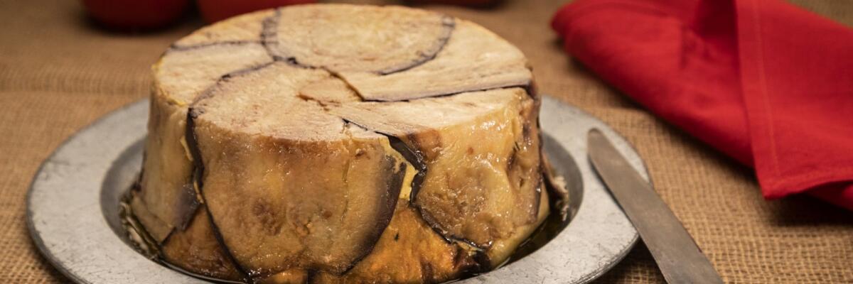 A timbale layered with strips of eggplant sits on a silver serving platter.