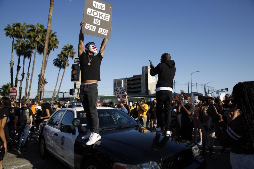 LOS ANGELES, CA - MAY 27: Two people stand on a police vehicle during a Black Lives Matter protest in downtown on Wednesday, May 27, 2020 in Los Angeles, CA. (Dania Maxwell / Los Angeles Times)