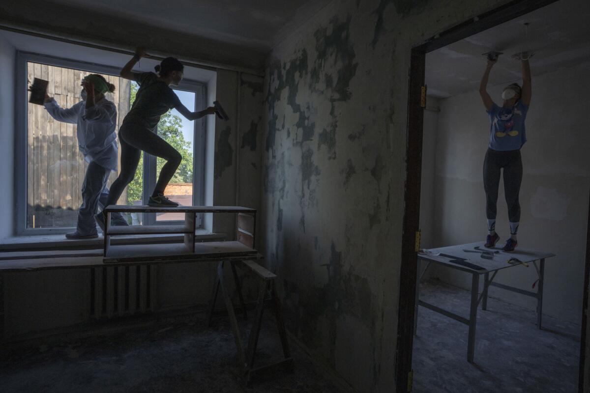 Women work to reconstruct a damaged fire department from Russian strikes