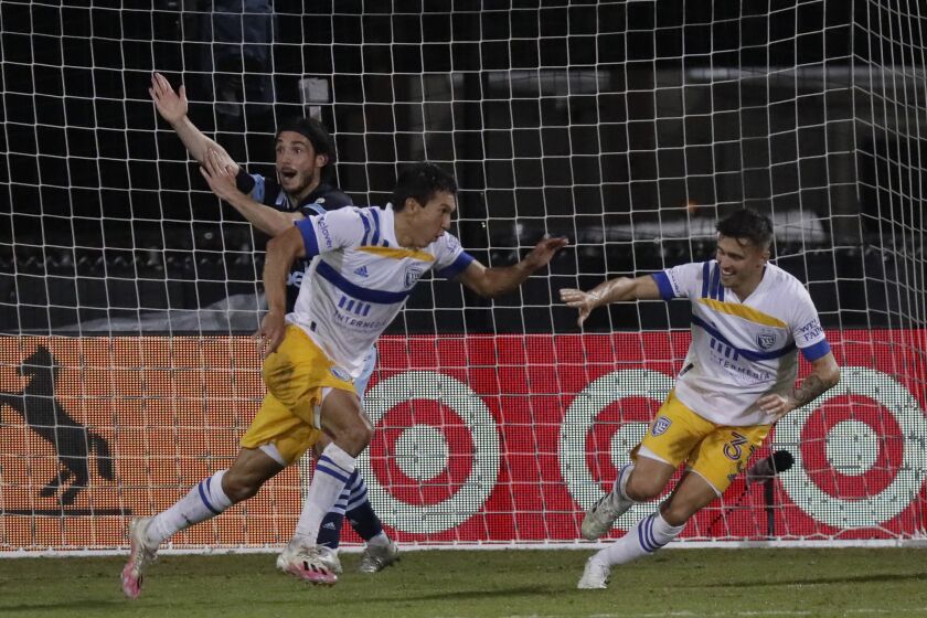 San Jose Earthquakes midfielder Shea Salinas, left foreground, celebrates his go-ahead and game-winning goal with defender Paul Marie as Vancouver Whitecaps midfielder Patrick Metcalfe reacts behind him during the second half of an MLS soccer match, Wednesday, July 15, 2020, in Kissimmee, Fla. (AP Photo/John Raoux)