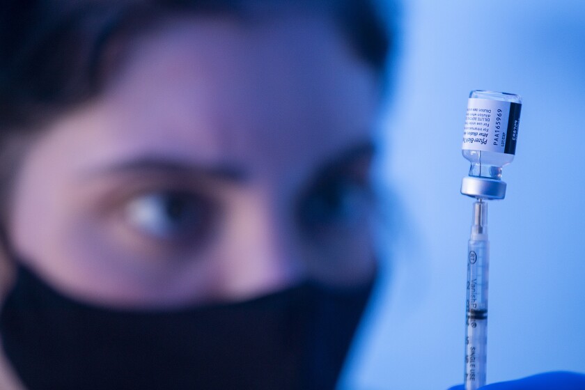A masked student looks at a vial