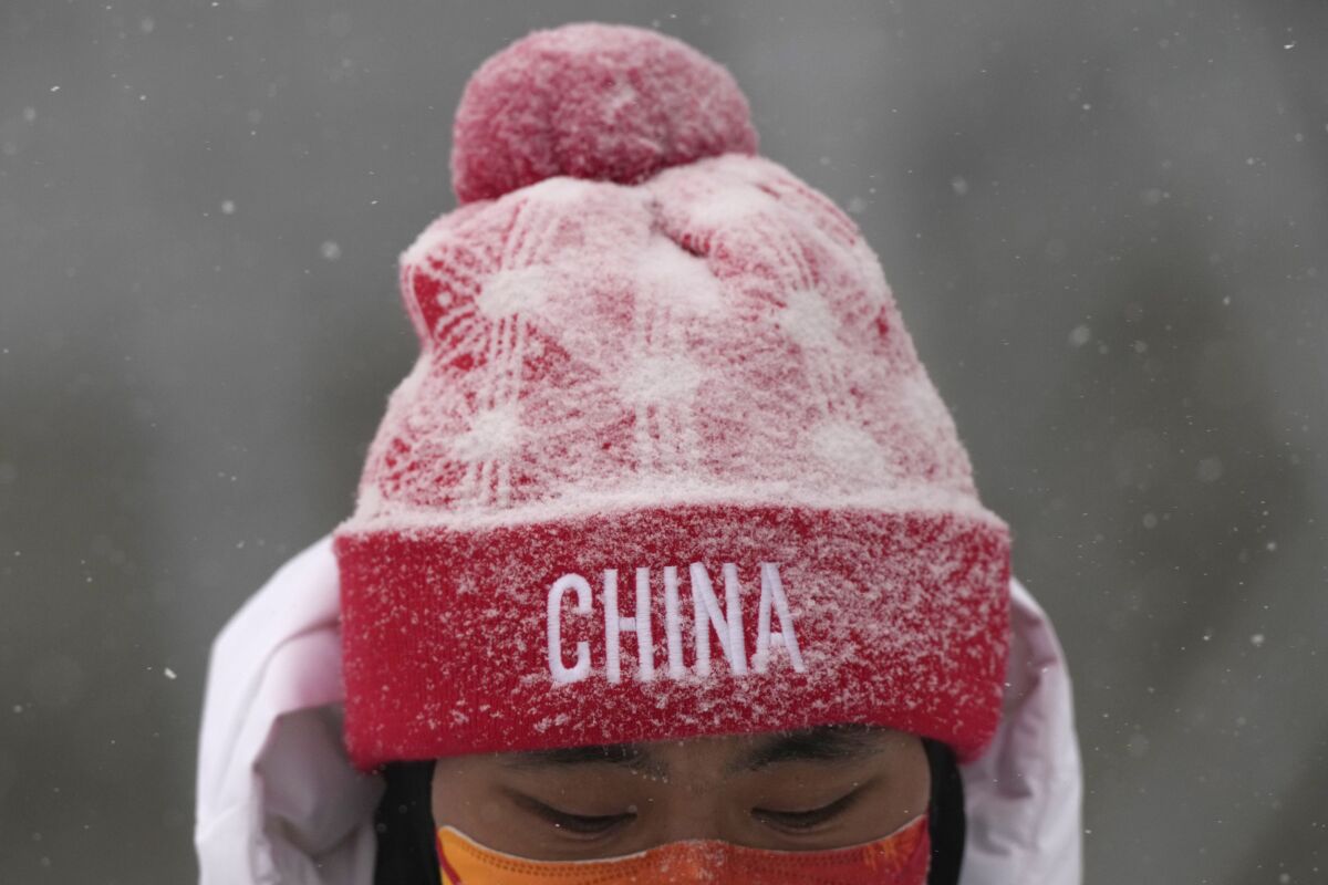 A member of China's team stands in the snow as the start of the women's slopestyle qualification is postponed.