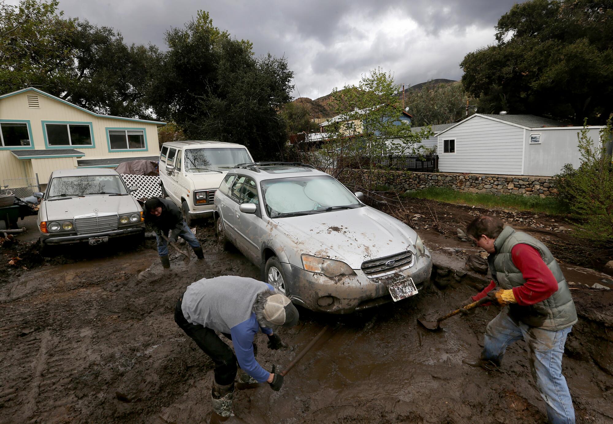 People shovel mud from under a car