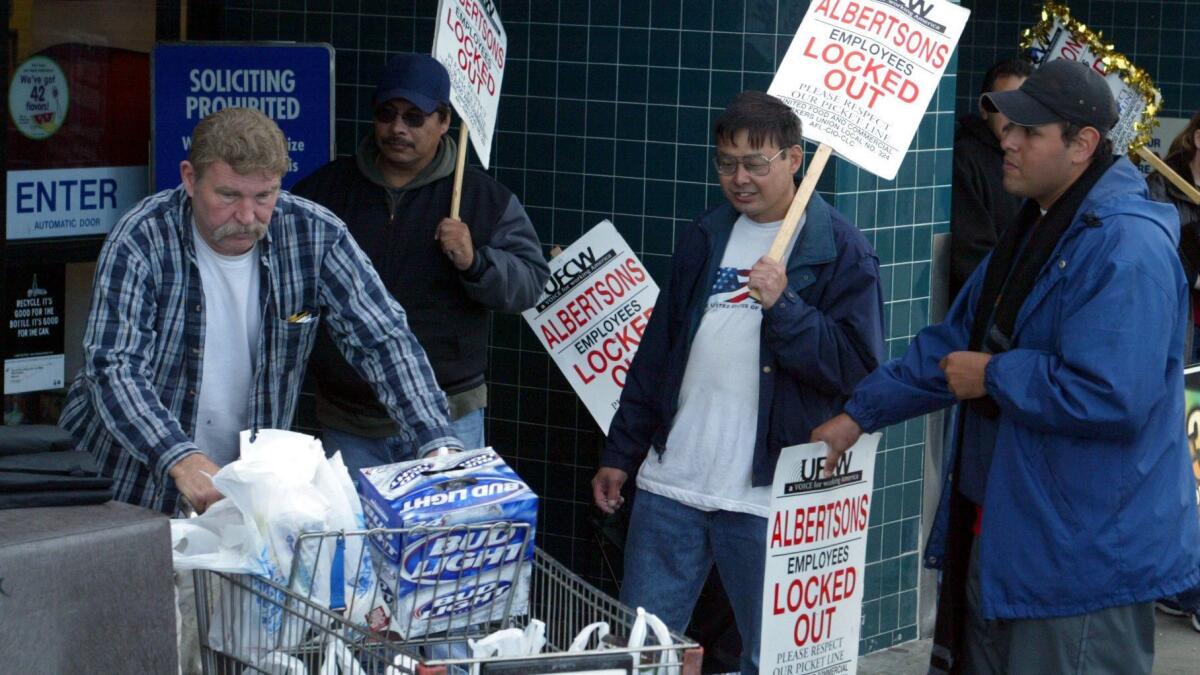 In December 2003, on the 61st day of that strike, a shopper passes picketing workers as he leaves an Albertsons store in Stanton.