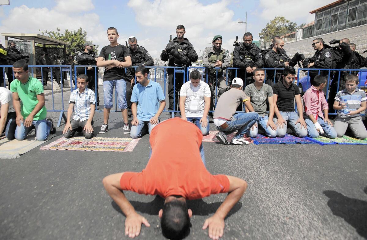 Israeli security forces stand guard as Palestinians perform Friday prayers in an East Jerusalem street Sept. 26. Israel restricted access to Al Aqsa mosque in a bid to stem violence.