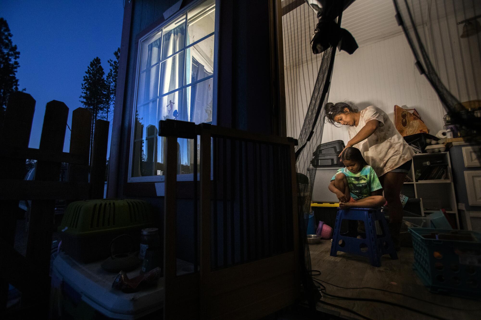 Inez Salinas brushes her daughter's hair inside their tiny home.