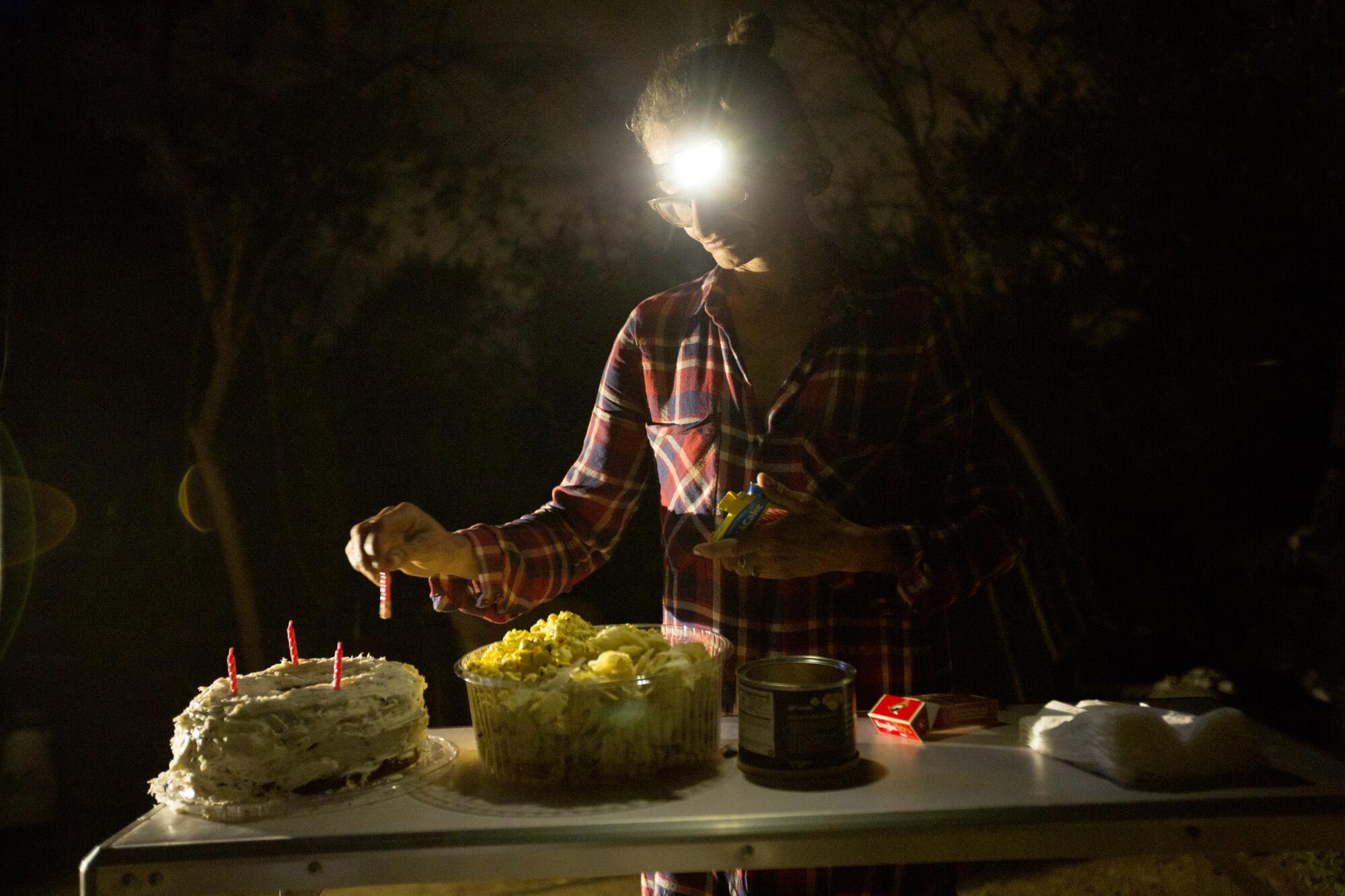 Elizabeth Bolton puts candles on a birthday cake for her boyfriend, Pablo Mawyin.