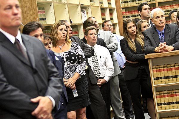Staff members listen as their boss Orange County District Attorney Tony Rackauckas addresses a press conference announcing charges against two Fullerton police officers for the beating death of 37-year-old homeless man Kelly Thomas.
