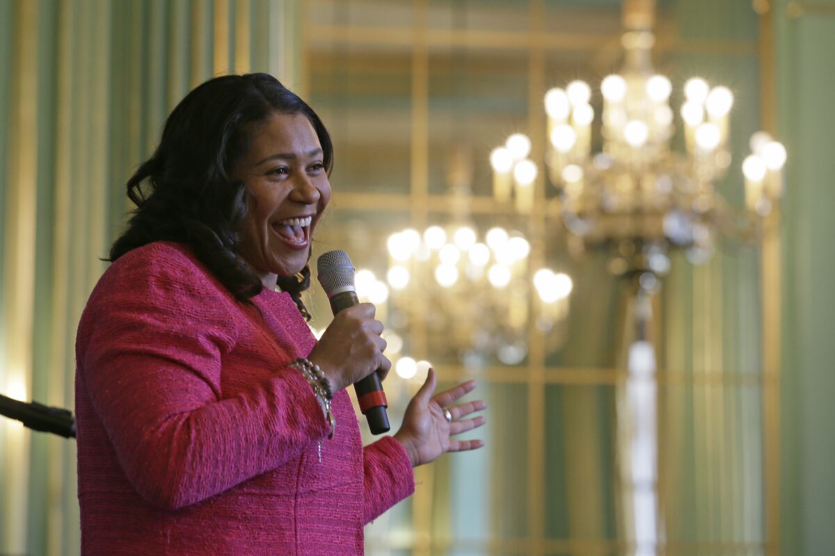 A woman holds a microphone in a room with multiple chandeliers