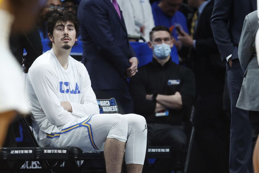 UCLA's Jaime Jaquez Jr. sits on the bench with ice on his ankle after leaving the court with an injury March 19, 2022.