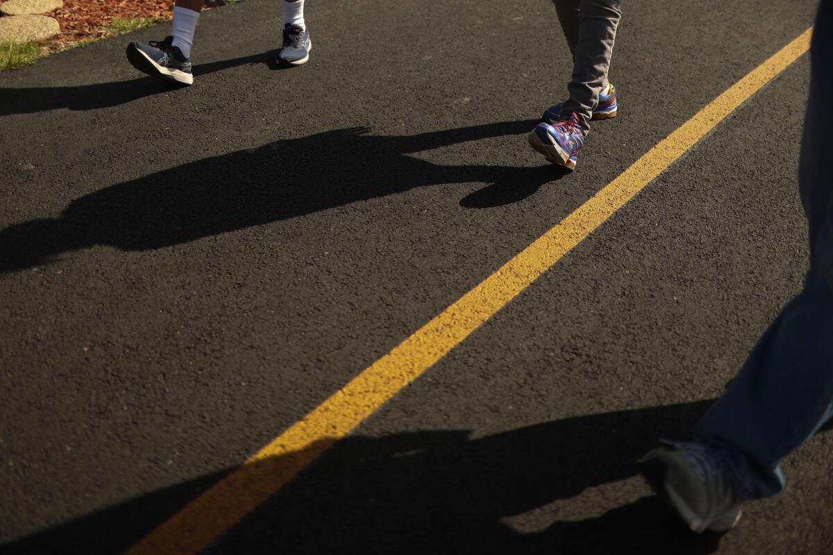 A view of people's shoes and shadows on a track