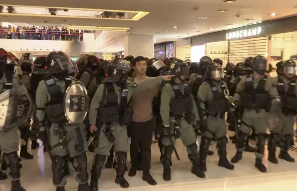 In this image made from video, a protester is arrested by police at a shopping mall in Sha Tin district in Hong Kong, while shoppers watch from balconies above Sunday.