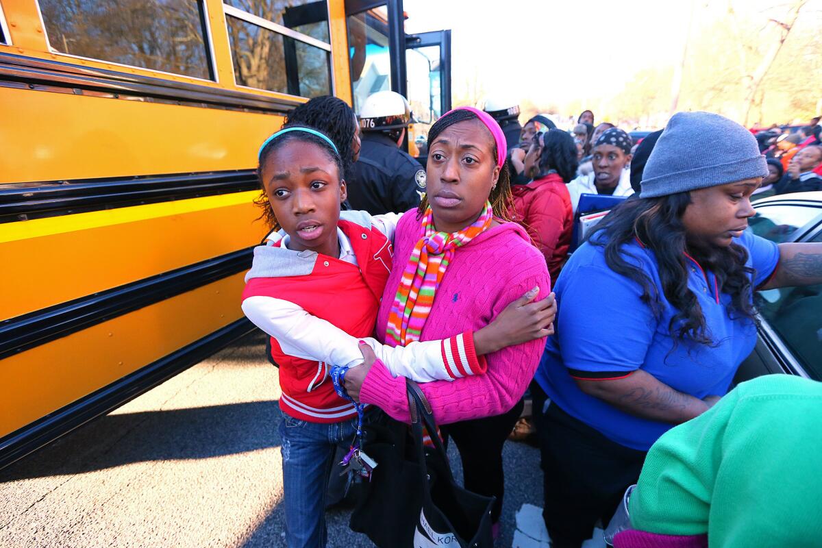 Tiffany Myricle, 37, leads her daughter Xavia Denise Myricle away from her school bus after a shooting at Price Middle School in Atlanta.