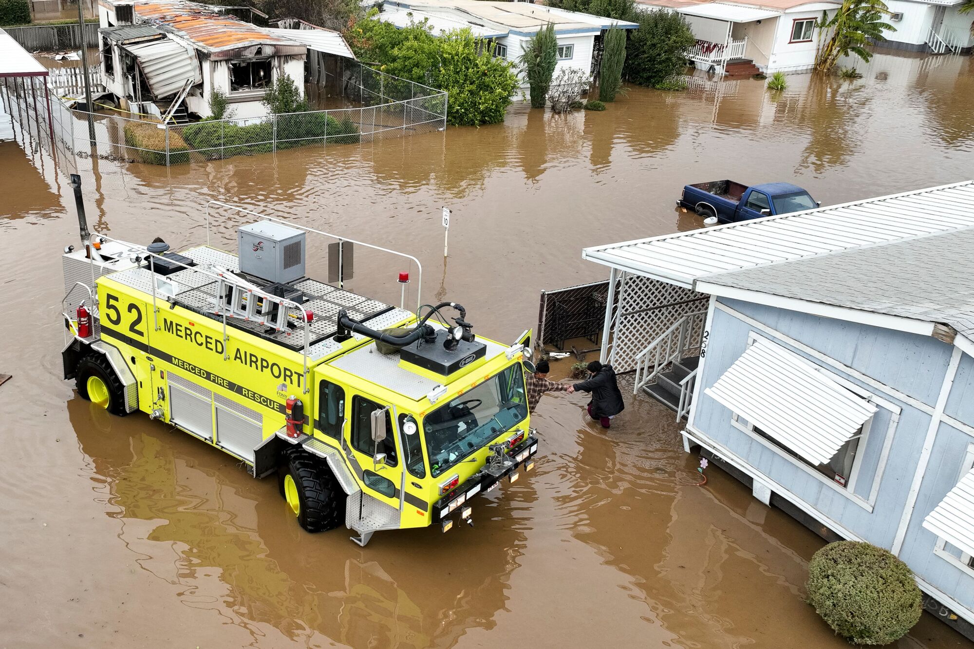 A rescue crew assists a stranded resident in a flooded neighborhood.