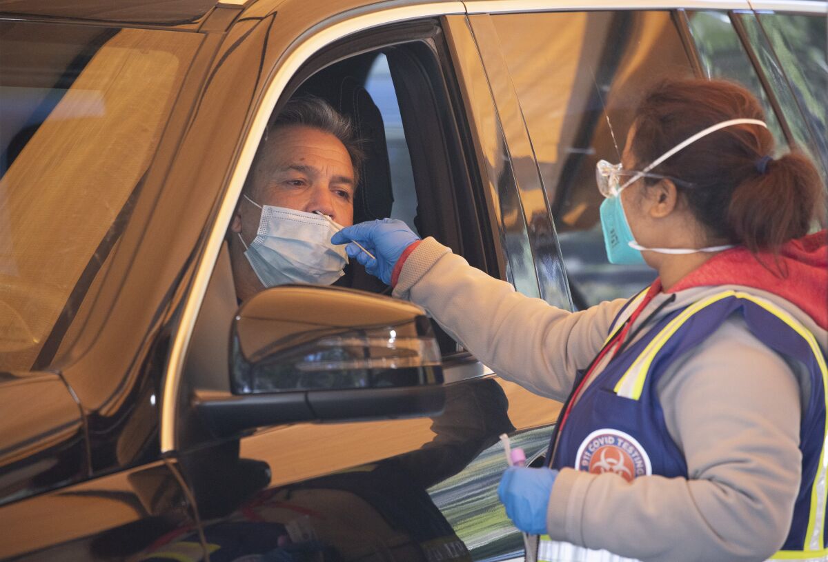 A person gets a COVID-19 swab test while sitting in a car.