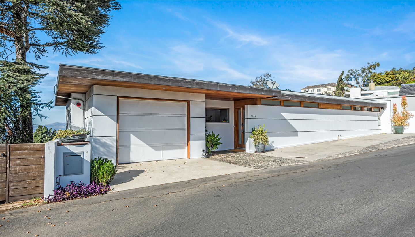 The exterior shows a garage and wall on a sloping street.