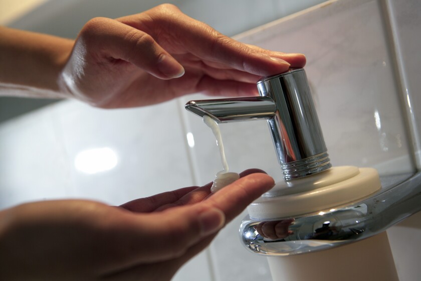 Hands under soap dispenser