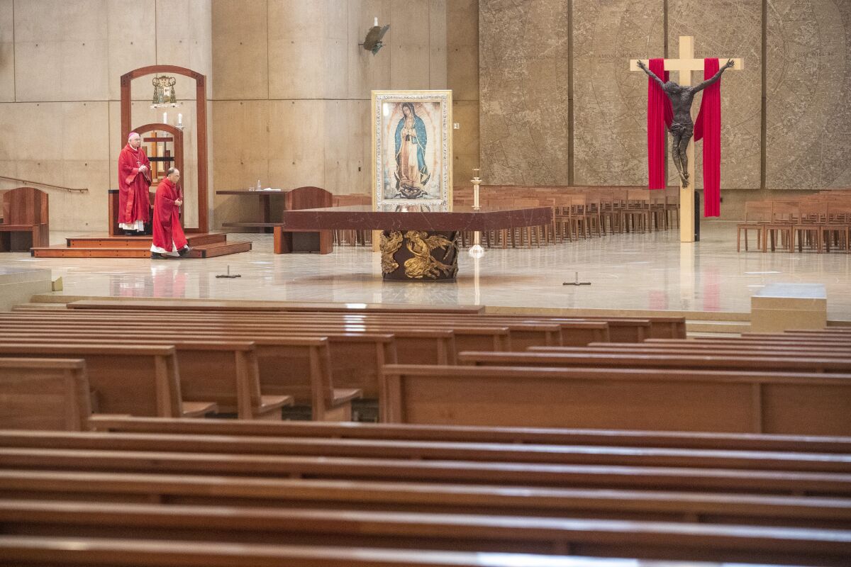 The interior of a cathedral with two priests in red robes walking toward the cross