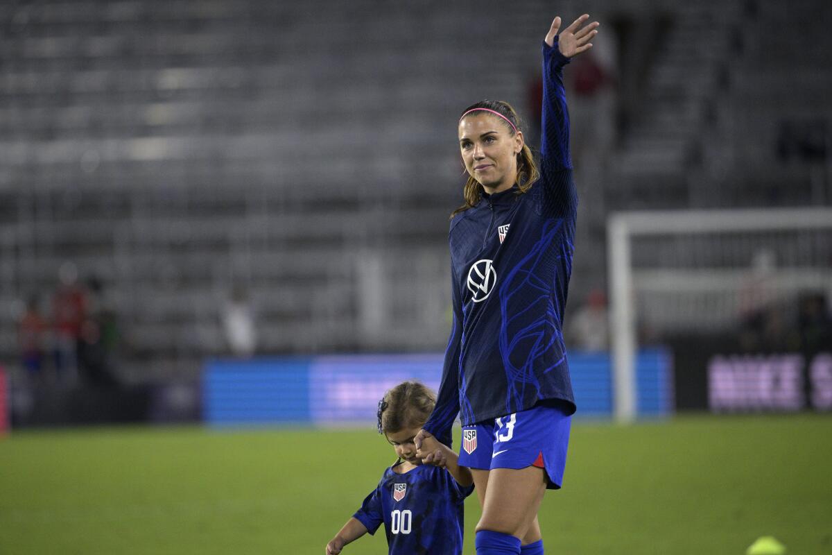 U.S. forward Alex Morgan, right, walks off the pitch with her daughter, Charlie Elena Carrasco