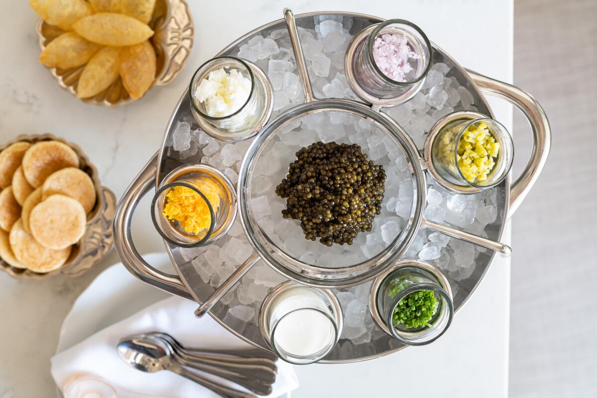 Small dishes surround caviar on a round tray of ice 