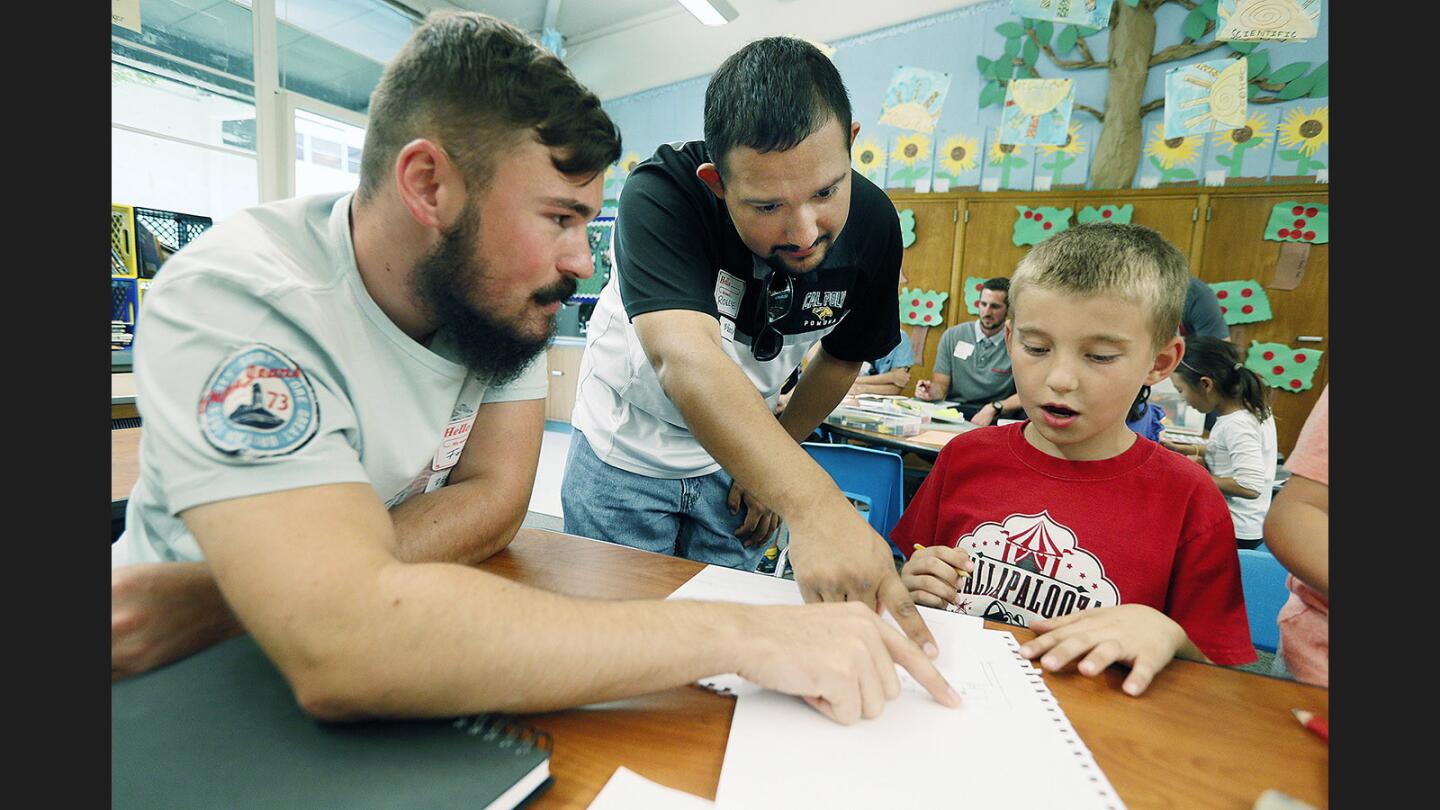 Cal Poly Pomona architecture students Fabian Muuhs and Rollie Corria work with Logan Smith, 7, with one of his drawings of his ideas for the ideal classroom at Palm Crest Elementary School on Friday, September 29, 2017. A group of architecture students from Cal Poly Pomona worked with students in Meredith Beyer's second grade classroom to harvest ideas from the young minds about what an ideal classroom would look like.