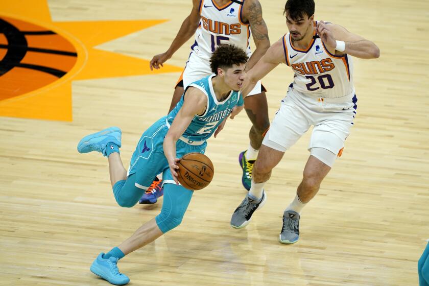 Charlotte Hornets guard LaMelo Ball (2) drives as Phoenix Suns forward Dario Saric (20) defends during the first half of an NBA basketball game, Wednesday, Feb. 24, 2021, in Phoenix. (AP Photo/Matt York)