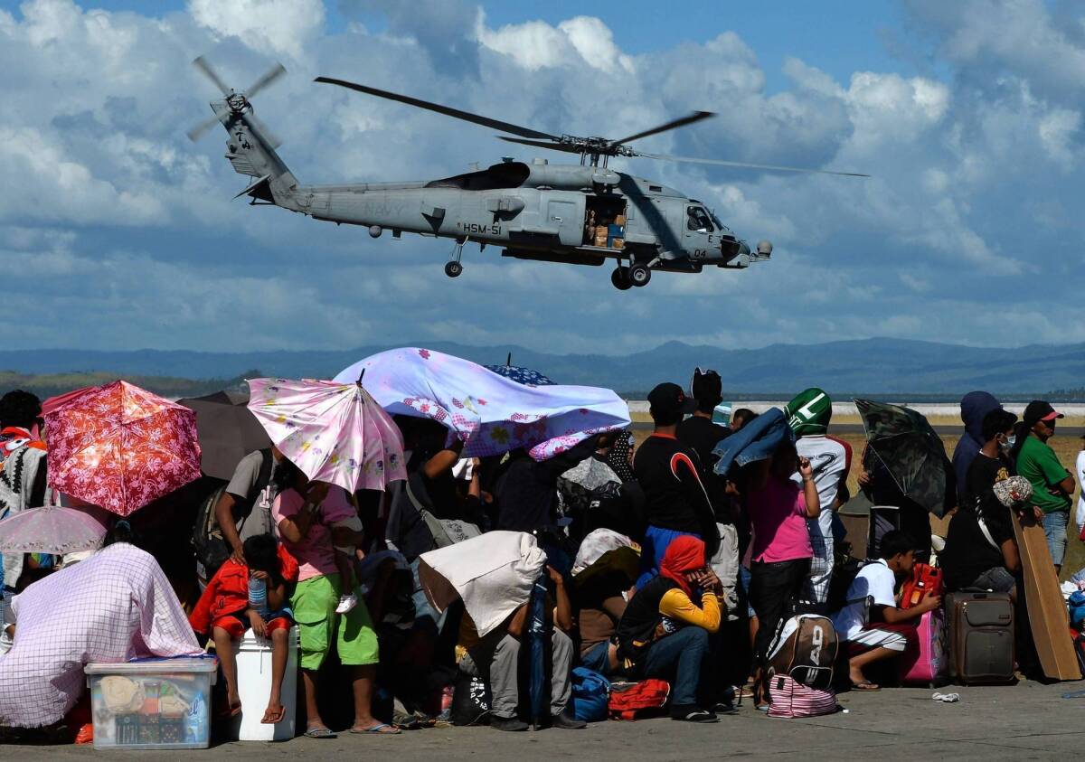 A U.S. Navy helicopter flies over the Tacloban airport. With a U.N. agency now putting the death toll at 4,460, the Philippine government is under fire for what critics say is the slow pace of its official relief effort.