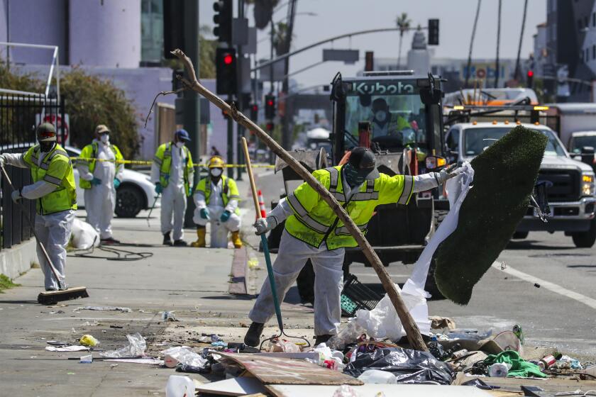 Los Angeles , CA - April 05: L.A. Sanitation Bureau crew clean up a homeless encampment on the sidewalk along Hollywood Blvd. on Tuesday, April 5, 2022 in Los Angeles , CA. (Irfan Khan / Los Angeles Times)