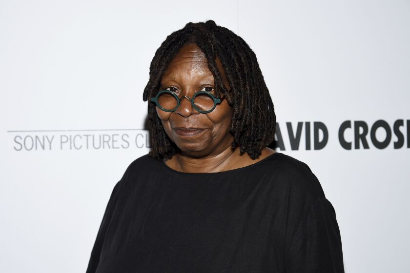 Whoopi Goldberg posing in round glasses and a black shirt