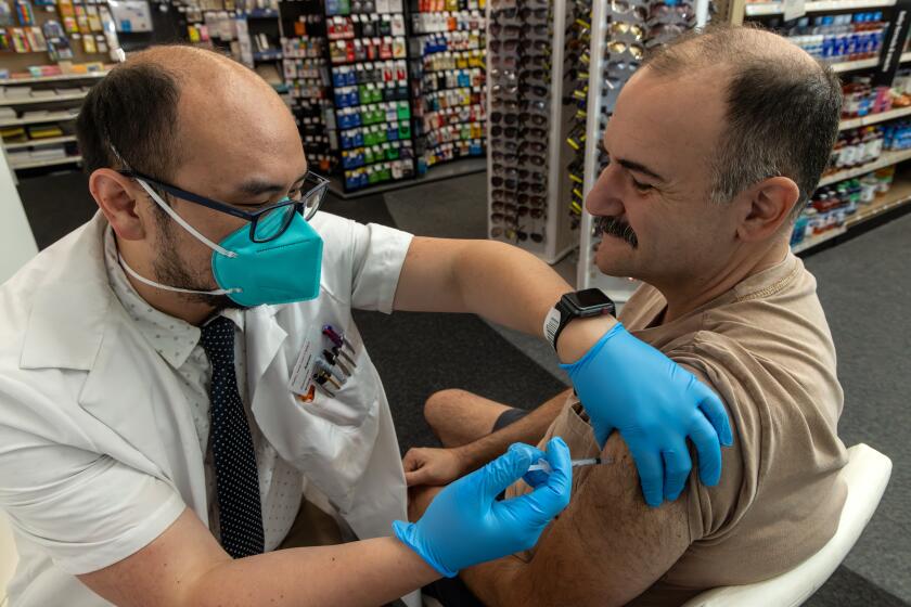 EAGLE ROCK, CA - SEPTEMBER 14: Pharmacist Aaron Sun administers new vaccine COMIRNATY (COVID-19 Vaccine, mRNA) by Pfizer, to Jimmy Smagula at CVS Pharmacy in Eagle Rock, CA. (Irfan Khan / Los Angeles Times)