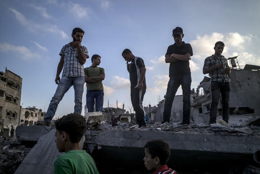 Palestinians stand atop a destroyed building in the devastated Shejaiya neighborhood of Gaza City on Aug. 6.
