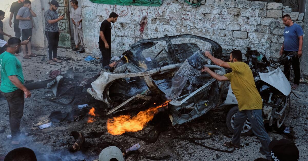 Photo: latimes.com EDS NOTE: GRAPHIC CONTENT - Palestinians try to extinguish a burning car after an Israeli military strike in Gaza City