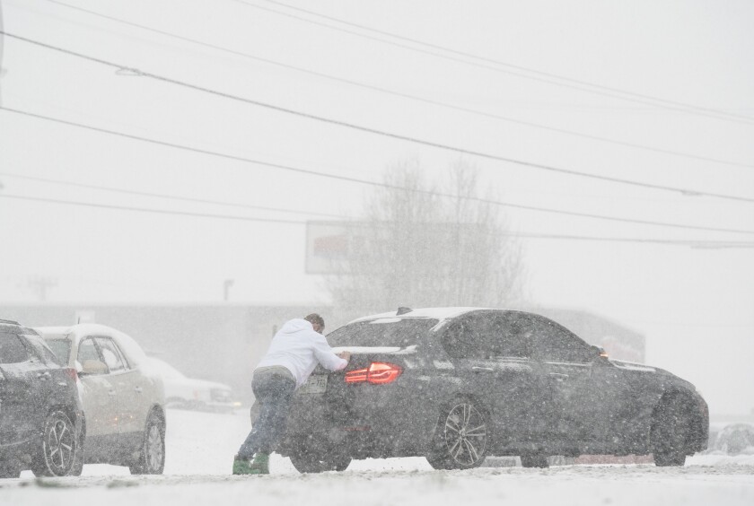 A motorist is pushed through snow by a man, Thursday, Jan. 6, 2022 in Nashville, Tenn. A winter storm blanketed parts of the South with quick-falling snow, freezing rain and sleet Thursday, tying up some roads in Tennessee as the system tracked a path through Appalachia toward the Mid-Atlantic and Northeast. (George Walker IV /The Tennessean via AP)