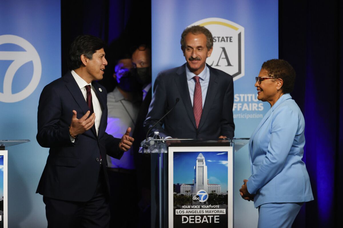 Kevin de León, left, speaks with Mike Feuer and Karen Bass at the start of Sunday's mayoral debate.