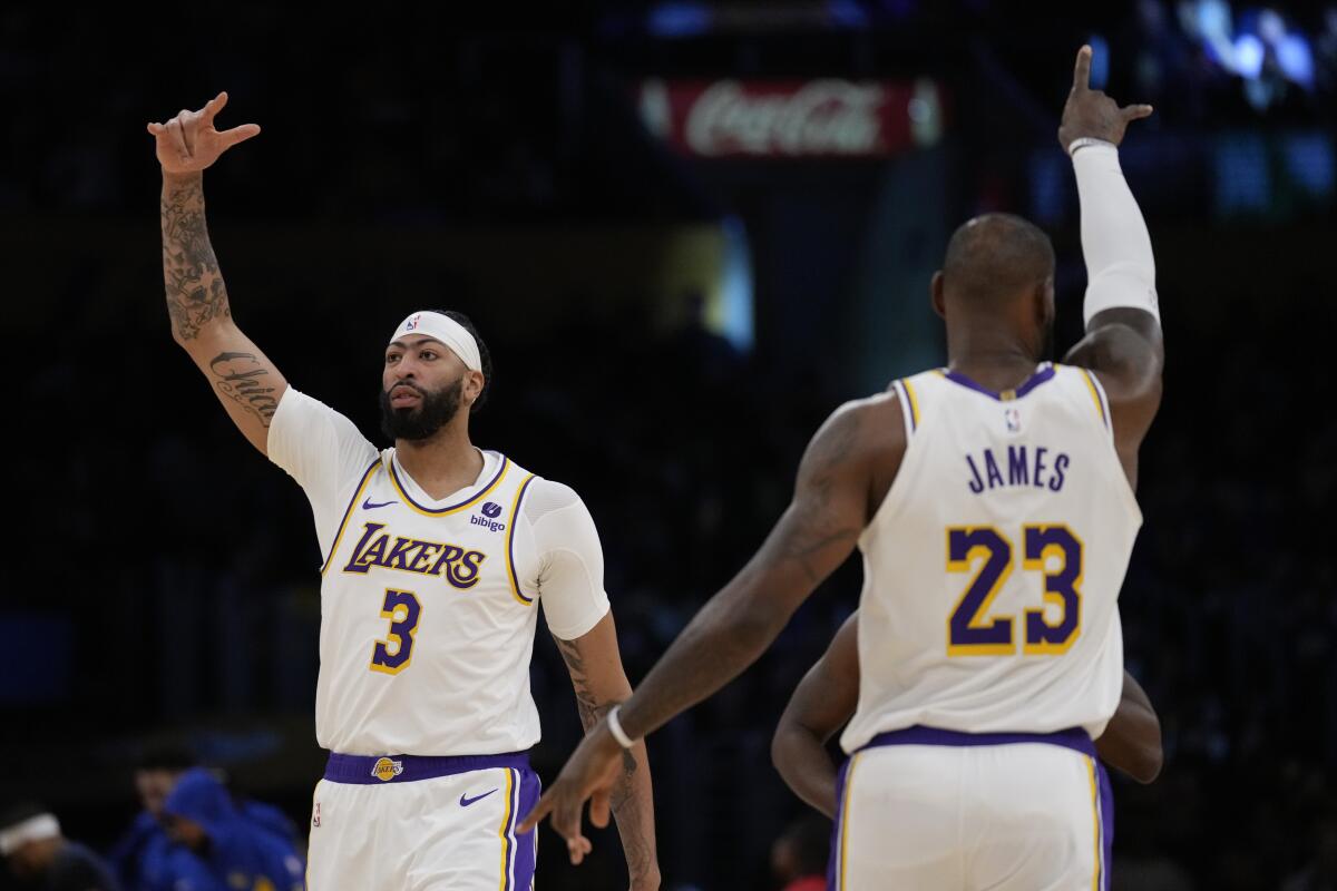 Lakers stars Anthony Davis, left, and LeBron James gesture before Saturday's game against the Warriors.