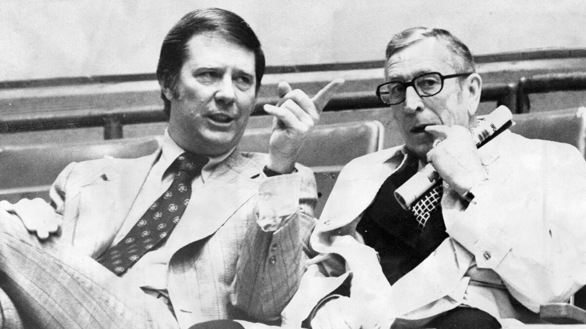 Coaches Bob Boyd, left, of USC and John Wooden of UCLA talk in the stands before a game in March 1974.
