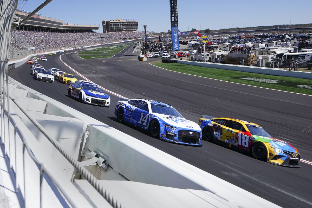 NASCAR Cup Series drivers Chase Briscoe (14) and Kyle Busch (18) race into the first turn in the NASCAR Cup Series auto race at Atlanta Motor Speedway in Hampton, Ga., Sunday, March 20, 2022, (AP Photo/John Bazemore)