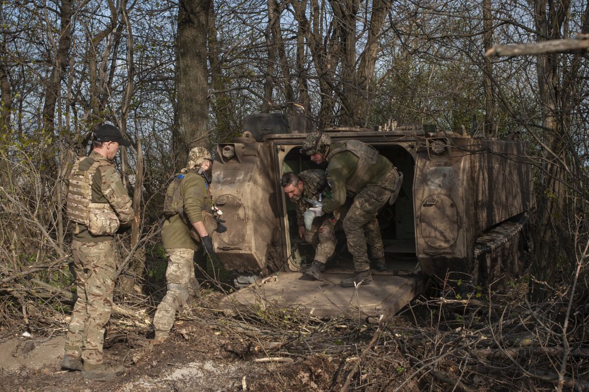 Askeri sağlık görevlileri, ormanlık bir alanda yaralı bir askerin araçtan inmesine yardım ediyor.