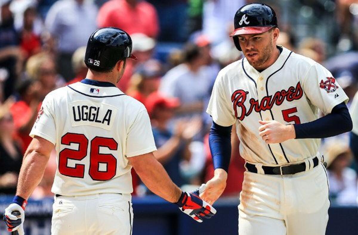 Braves first baseman Freddie Freeman is congratulated by second baseman Dan Uggla after scoring a run against the Philadelphia Phillies at Turner Field on Sunday.