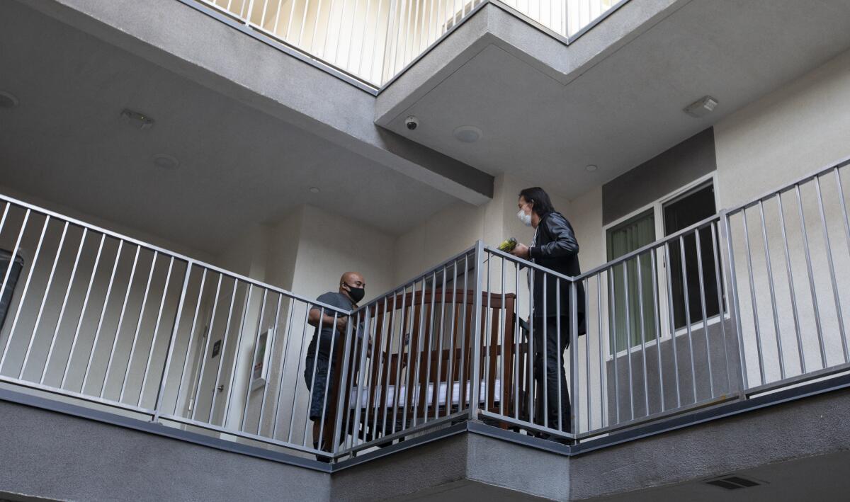 Workers Jose Ruiz, left, and Frank Chavez move a new crib into new housing in North Hills.