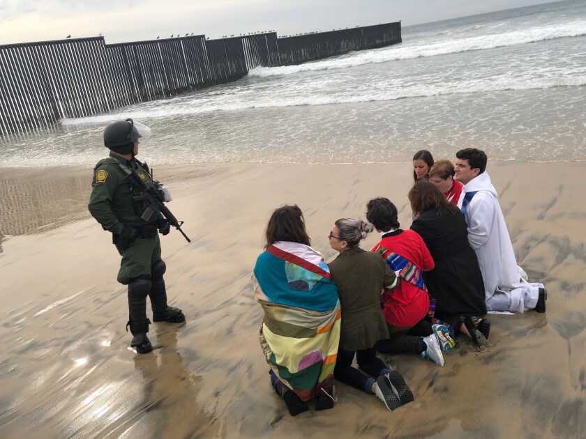 Un agente de CBP custodia personas detenidas frente al mar fronterizo.