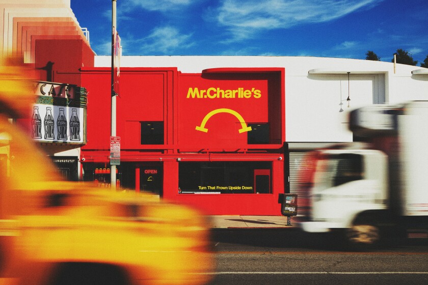 The red exterior of a restaurant with "Mr. Charlie's" painted in yellow above a yellow frown.