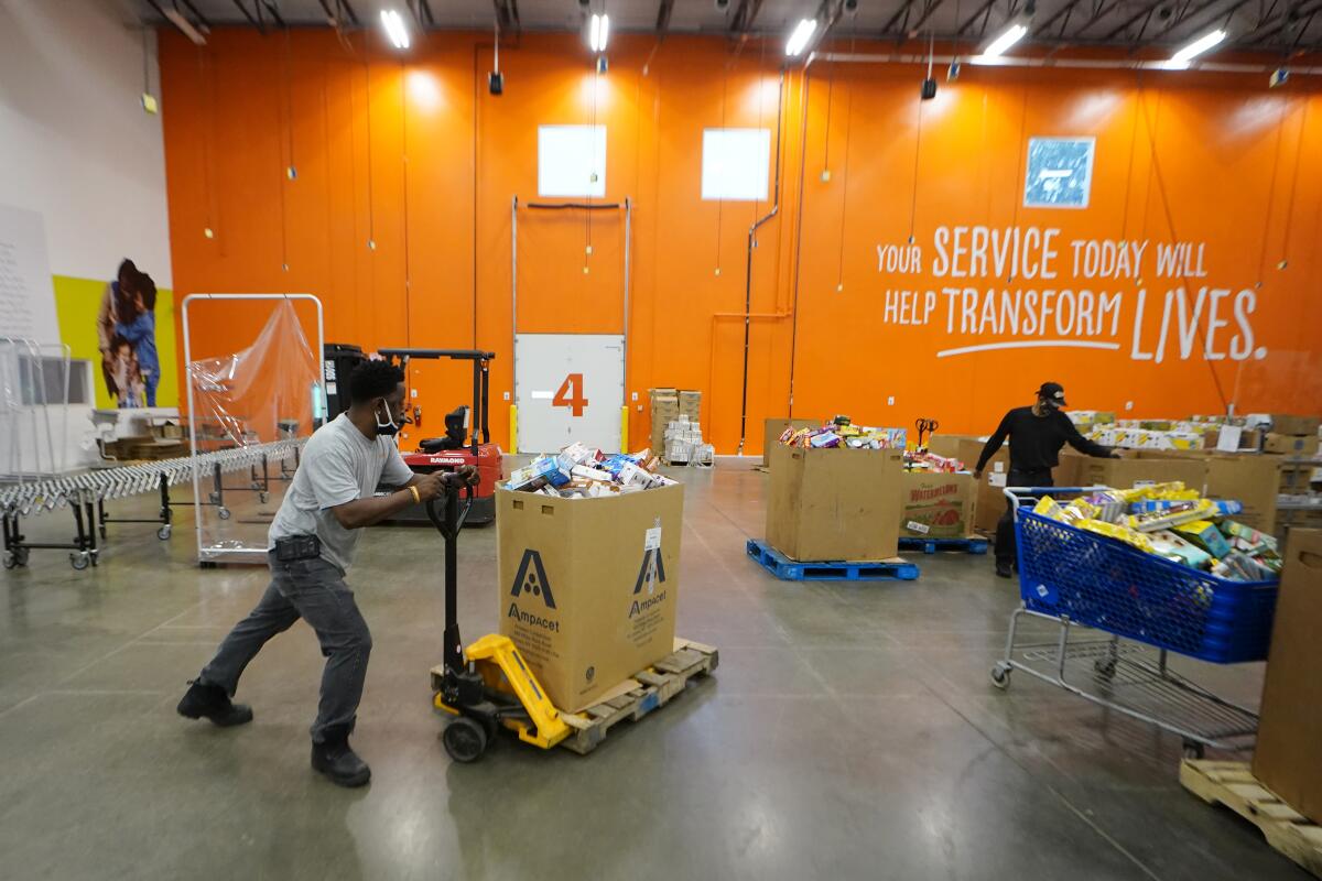 A man pushes a forklift carrying a large pallet of items at a food bank in College Park, Ga.