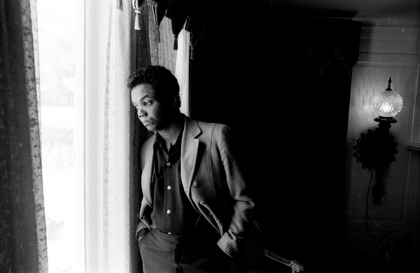 Black and white photo of a man staring out a window 