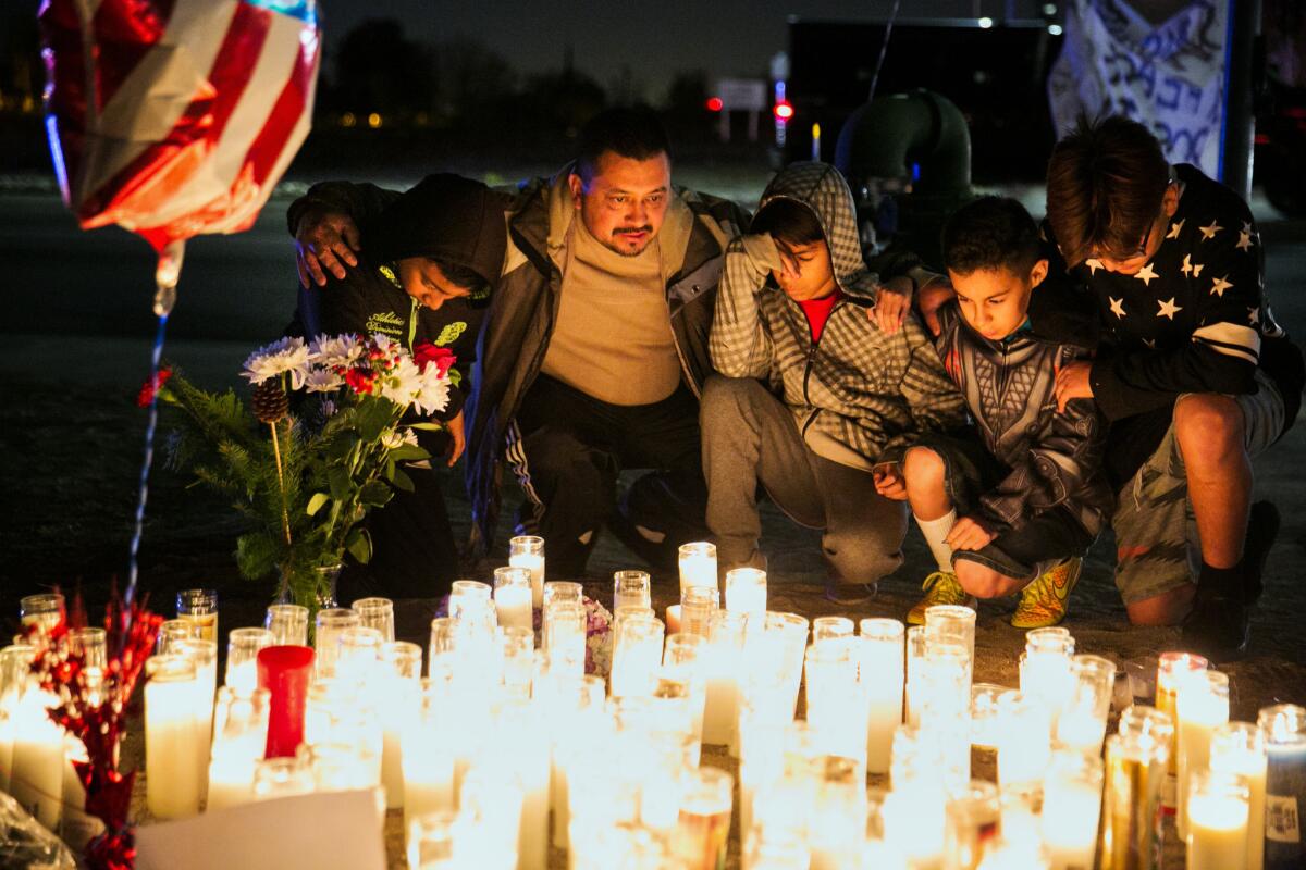 People kneel in prayer for victims of the recent mass shootings at the Inland Regional Center, in San Bernardino.