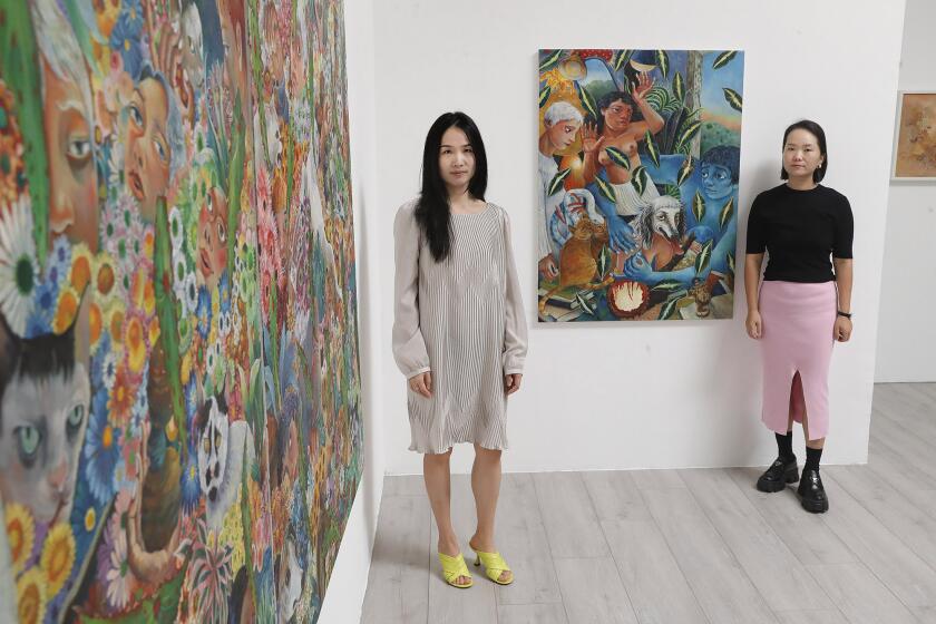 Co-founders Lorraine Han and Dan Yang, from left, stand with OSpring #1 and OCatOs Eye Autumn CamelliaO by artist Bing Liu at the Unveil Gallery in Irvine. The pair have launched the new gallery space, and intend to amplify diverse voices and provide a platform for emerging and established regional, national, and international artists. Their inaugural exhibition.