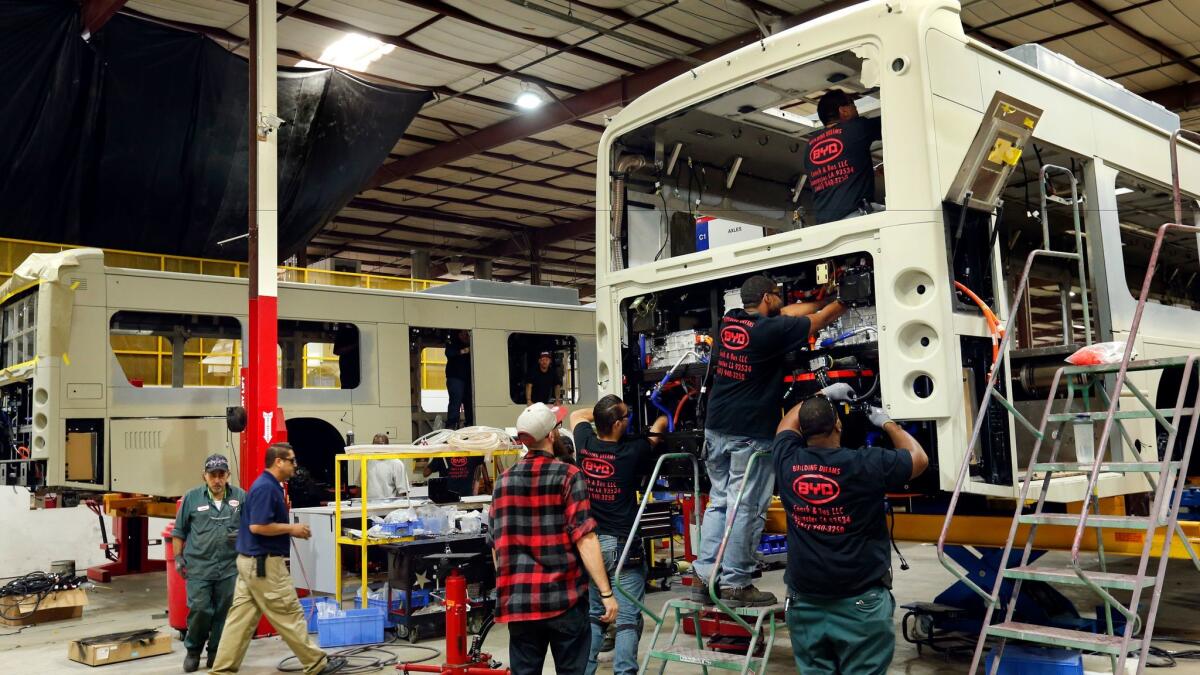 Workers install the cooling system on a 45-foot-long electric bus at BYD's manufacturing plant in Lancaster on Sept. 22, 2016.