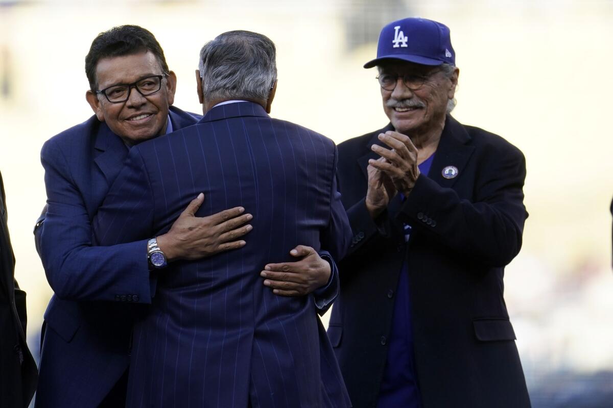 Jaime Jarrín is hugged by broadcast partner and former Dodgers pitcher Fernando Valenzuela as actor Edward James Olmos claps.