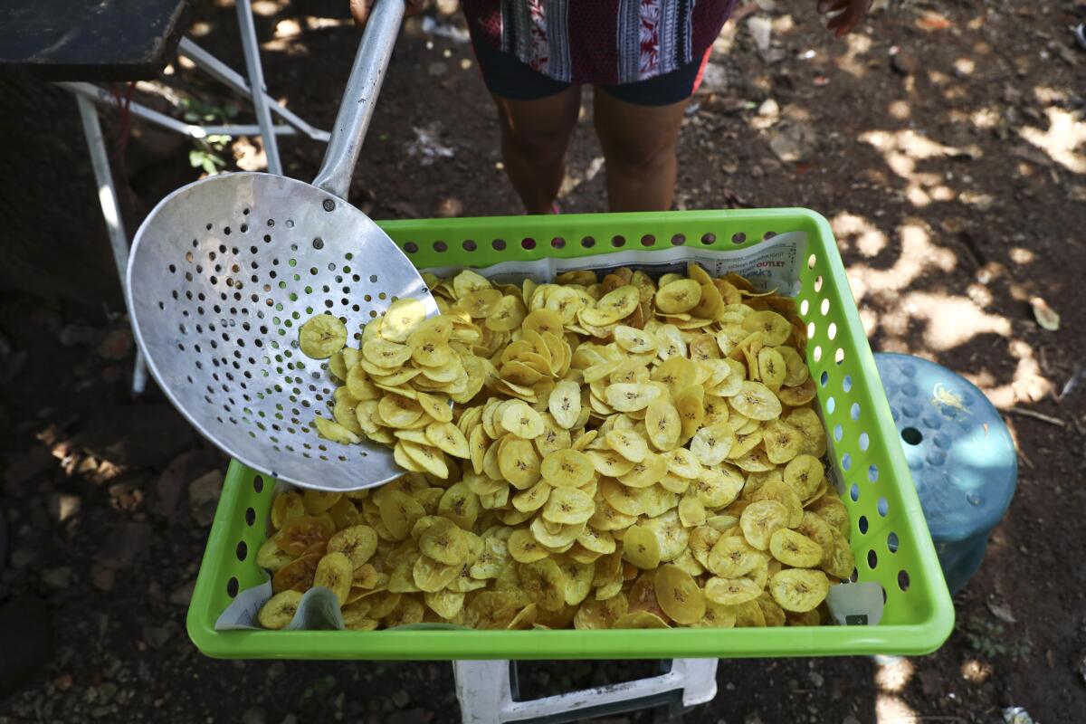 En esta foto del 10 de octubre de 2019, María Teresa Carballo fríe rebanadas de plátano fuera de su casa en Santa Ana, El Salvador. (Foto AP/Eduardo Verdugo)